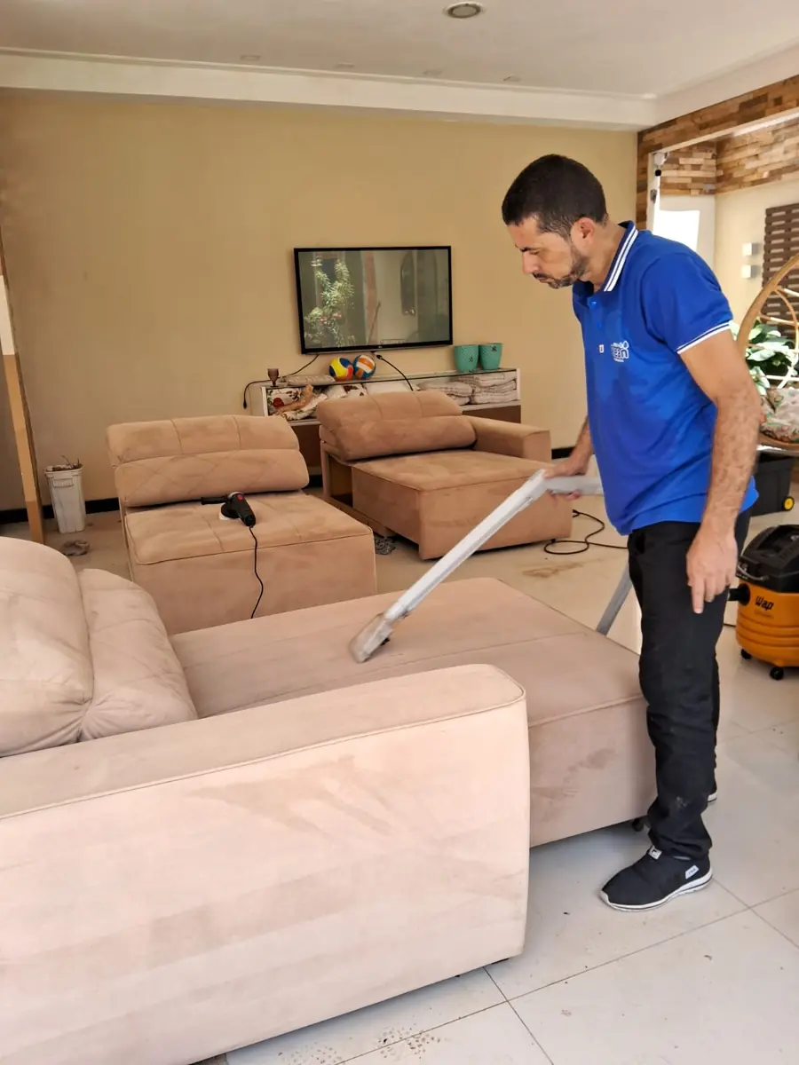 Técnico da Multi Clean higienizando um sofá claro com extratora na casa de um cliente